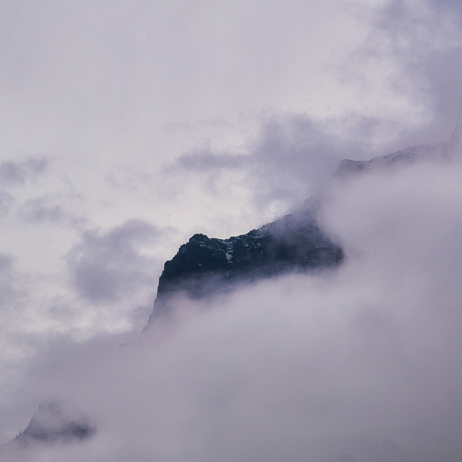 A mountain peak rises sharply above a sea of clouds.