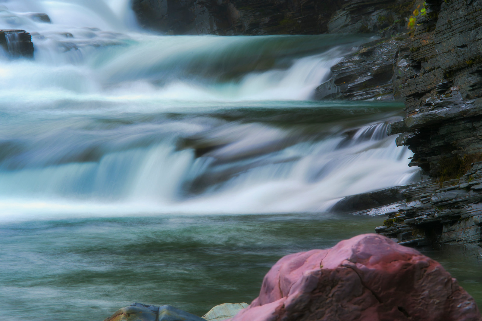 Rapid, frothy water cascades over rocky ledges in a powerful waterfall.